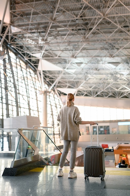 Concept de voyage. Femme de voyageurs marchant avec un bagage au terminal de l'aéroport.