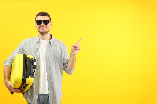 Concept de voyage avec jeune homme sur fond jaune, espace pour le texte.