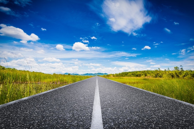 Concept de voyage avec longue route avec champ vert et ciel bleu