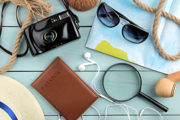 Concept de voyage Lunettes, appareil photo, passeport, carte et coquillages sur une table en bois bleue. relaxation. vacances. vue de dessus