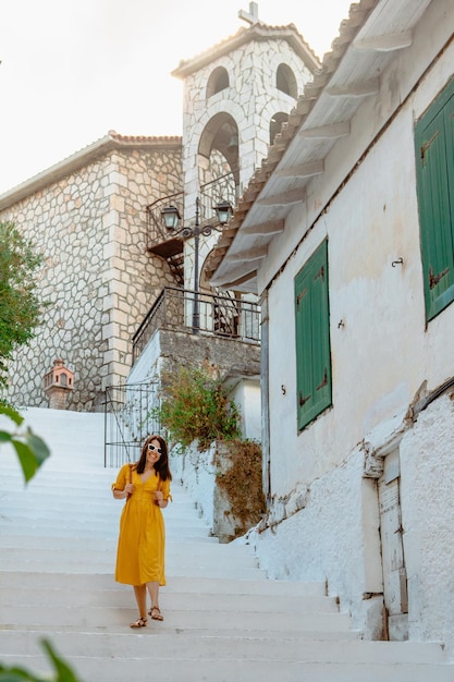 Concept de voyage et de mode de vie actif Jeune femme voyageuse en robe jaune marchant dans la vieille ville de Grèce