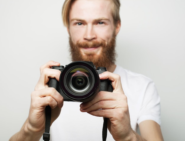 Concept de voyage, de technologie et de style de vie : jeune photographe barbu prenant des photos avec un appareil photo numérique.