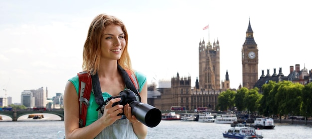 concept de voyage, de tourisme et de personnes - jeune femme heureuse avec sac à dos et appareil photo photographiant sur la rue de la ville de londres et le fond de la tour big ben