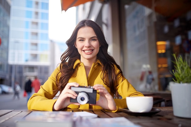 concept de voyage, de tourisme, de photographie, de loisirs et de personnes - heureuse jeune femme touristique ou adolescente avec caméra et guide buvant du cacao à la terrasse du café de la rue de la ville