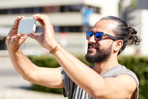 concept de voyage, de tourisme, de technologie et de personnes - homme souriant prenant une vidéo ou un selfie par smartphone dans la rue de la ville d'été