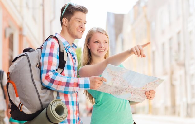 concept de voyage, de vacances et d'amitié - couple souriant avec carte et sac à dos en ville