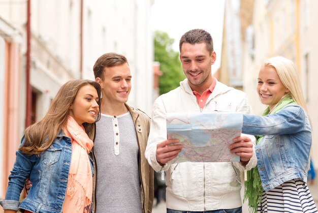 concept de voyage, de vacances et d'amitié - groupe d'amis souriants avec carte de la ville explorant la ville