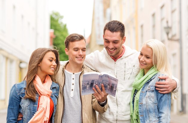 concept de voyage, de vacances et d'amitié - groupe d'amis souriants avec guide de la ville explorant la ville