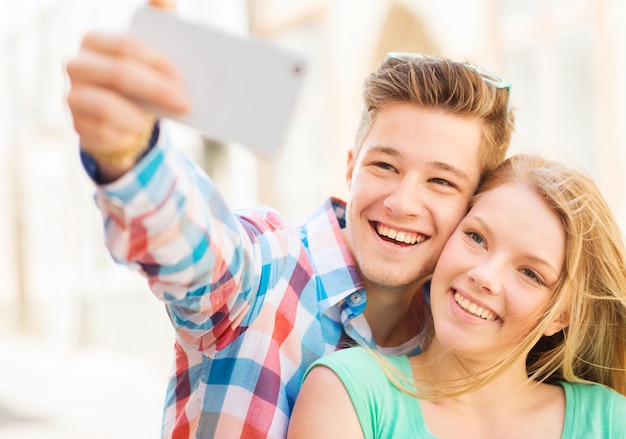 concept de voyage, de vacances, de technologie et d'amitié - couple souriant avec smartphone en ville