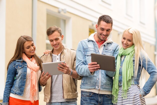 concept de voyage, de vacances, de technologie et d'amitié - groupe d'amis souriants avec des ordinateurs tablettes dans la ville