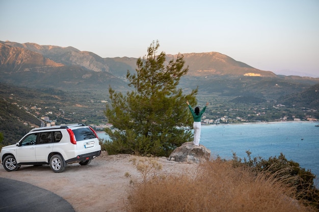 Concept de voyage en voiture femme debout sur la falaise regardant la baie de la mer