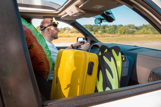 Concept de voyage en voiture de vacances en mer homme en masque de plongée conduisant une voiture pleine de sacs