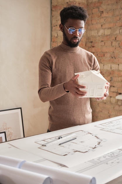 Photo concepteur de bâtiment créatif regardant le modèle d de maison