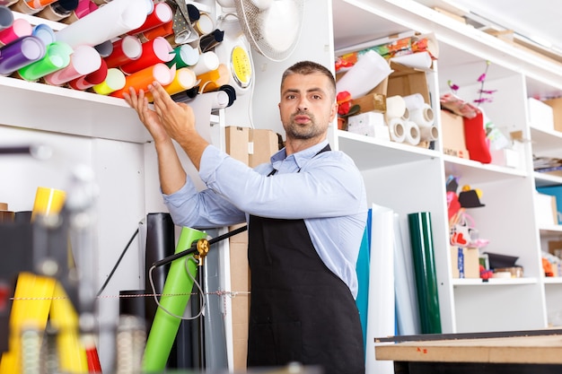 Photo concepteur d'homme et opérateur d'impression avec du papier vinyle à la fabrication d'impression