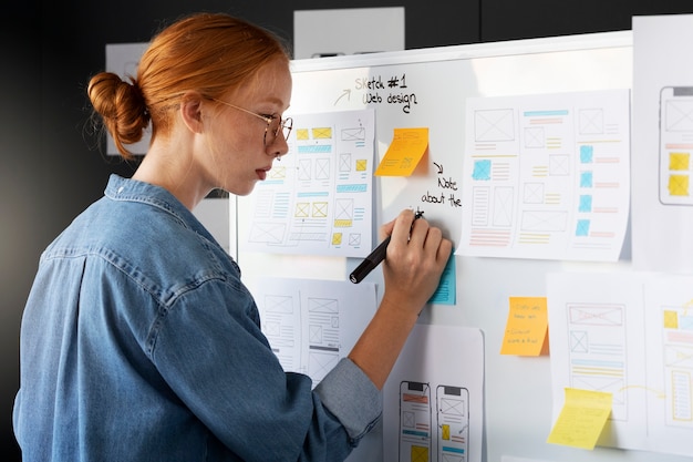 Photo concepteur de sites web féminin avec des papiers et des notes au bureau