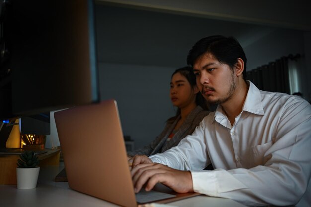 Des concepteurs de sites Web masculins et féminins travaillant sur un nouveau projet dans un bureau sombre