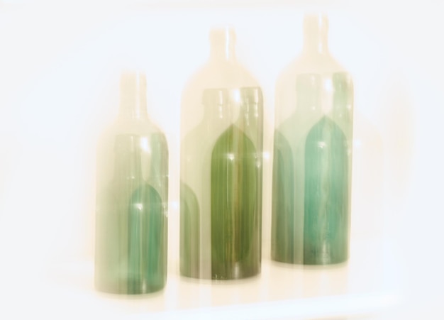Conception artistique de vieilles bouteilles en verre avec effet de mouvement flou isolé sur fond blanc Lumière colorée floue abstraite sur trois bouteilles en verre vert Effet d'exposition longue de la vision rêveuse ivre