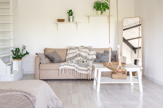 Conception de chambre de luxe dans un chalet rustique dans un style minimaliste. murs blancs, fenêtres panoramiques, éléments de décoration en bois au plafond, balançoires en corde au milieu d'une pièce spacieuse.