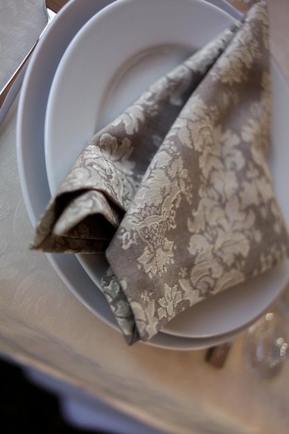 Conception classique de la table. Réglage de la table : serviette brune, couteau et fourchette, verres à vin. servi pour le dîner dans un restaurant chaleureux. Table dressée dans un restaurant élégant avec quelques verres à vin. flou artistique