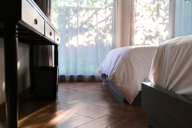 Photo conception de détail intérieur de la chambre à coucher matelas doux blanc avec plancher en bois et armoire de style ancien soleil du matin à travers le rideau de la fenêtre avec fond de jardin flou bokeh à l'extérieur salle d'émotion confortable et relaxante