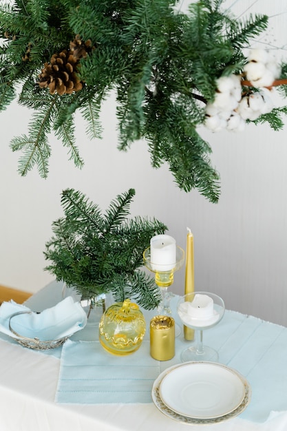 Conception esthétique pour Noël avec guirlande suspendue en pin nobilis, bougies et décorations de table.