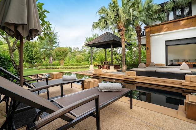 La conception extérieure de la maison, de la maison et de la villa comprend une piscine, un transat, un parasol et une serviette sur la terrasse de la piscine