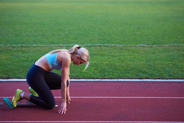 conception pixélisée d'une sprinteuse femme laissant des blocs de départ sur la piste d'athlétisme. Vue de côté. début explosif