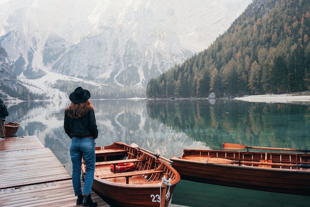 Conception touristique. Femme, dans, chapeau noir, apprécier, majestueux, paysage montagne, près, les, lac, à, bateaux