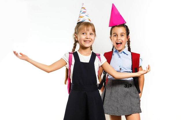 Concepts amusants pour l'enfance : deux petites écolières en chapeaux de fête d'anniversaire