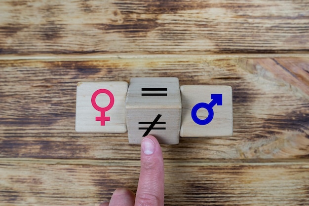 Concepts de cube en bois d'égalité des sexes avec symbole inégal changeant en signe égal