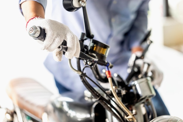 Concepts de réparation et d'entretien Homme réparant la moto dans l'atelier de réparation Mécanicien fixant et vérifiant la moto du système de freinage dans le garage de l'atelier