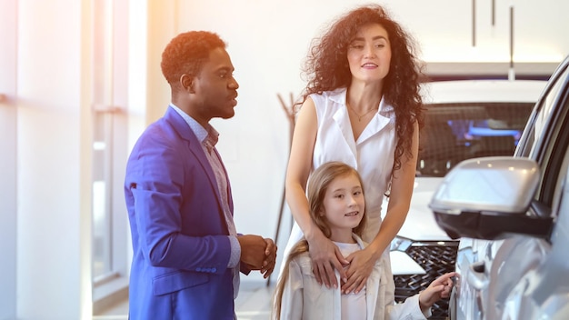 Un concessionnaire afro-américain montre une voiture à un client avec sa fille