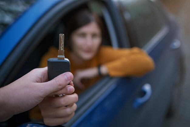 Concessionnaire automobile donnant une clé automobile à une femme asiatique pour un essai routier