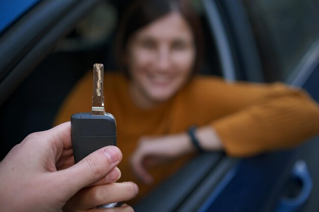 Concessionnaire automobile donnant une clé automobile à une femme asiatique pour un essai routier