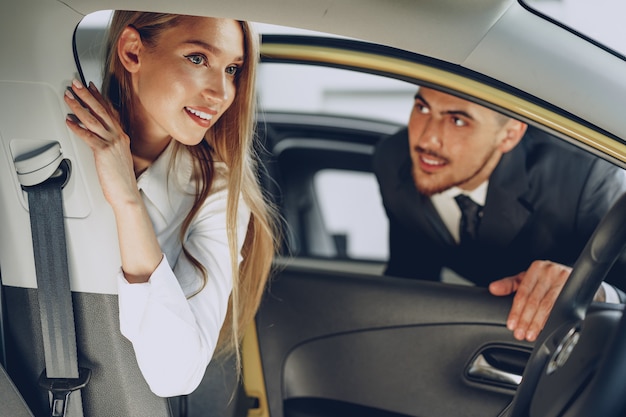 Concessionnaire automobile homme montrant une femme acheteuse une nouvelle voiture dans un salon de voiture