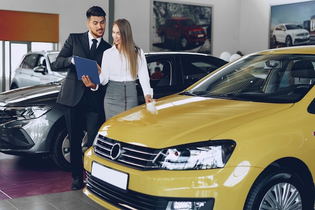 Concessionnaire automobile homme montrant une femme acheteuse une nouvelle voiture dans un salon de voiture