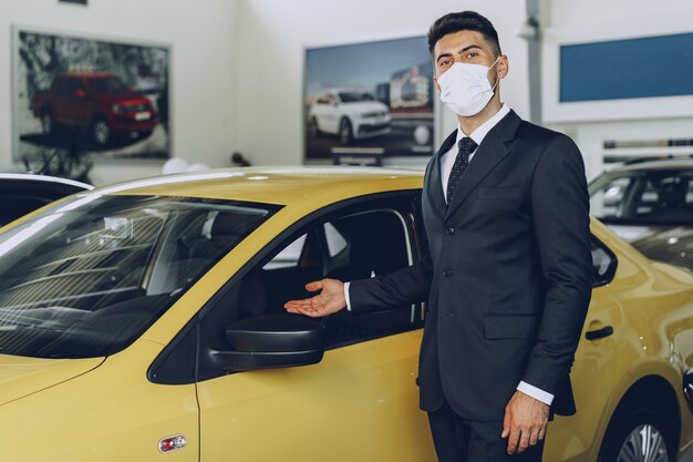 Concessionnaire automobile homme portant un masque médical de protection sur son lieu de travail