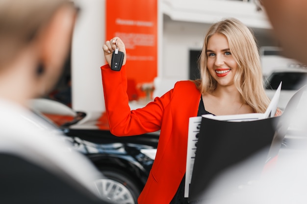 Photo concessionnaire automobile montrant une clé dans sa main et large closeup souriant.