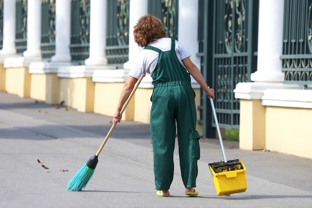 Le concierge nettoie le trottoir de la ville des feuilles tombées. travailler dans le domaine du nettoyage des rues
