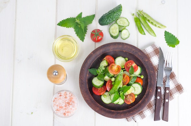 Concombre frais, tomate, pois verts sur un bol en céramique.