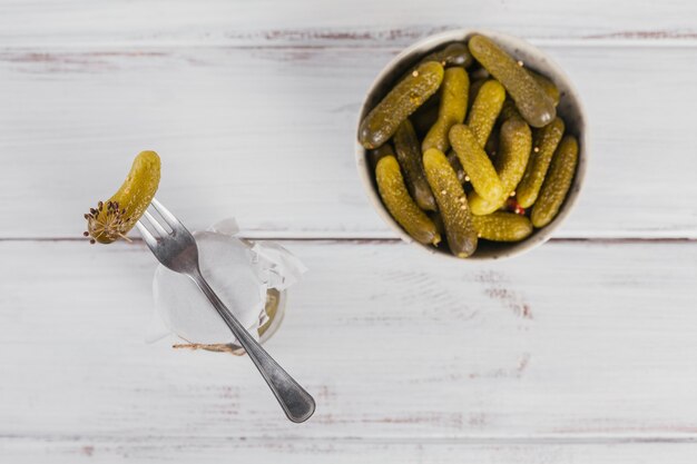 Concombre mariné de cornichons sur un bol de fourchette de légumes marinés sur un fond en bois blanc