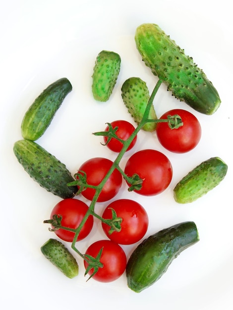 concombres frais et branches de tomates rouges isolées sur le blanc