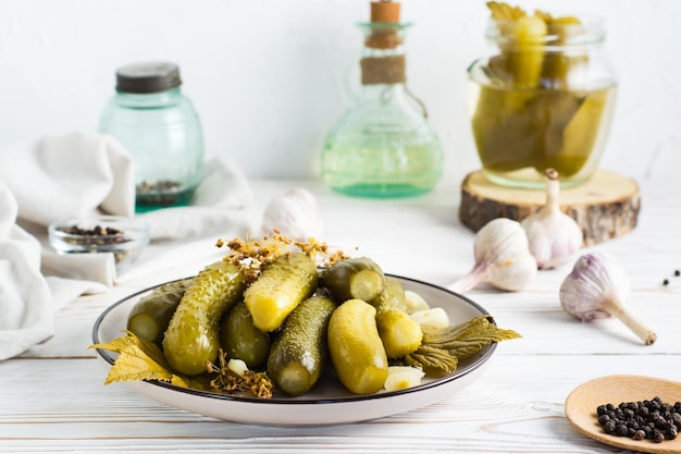 Concombres marinés sur une assiette et ingrédients pour la cuisson sur une table en bois