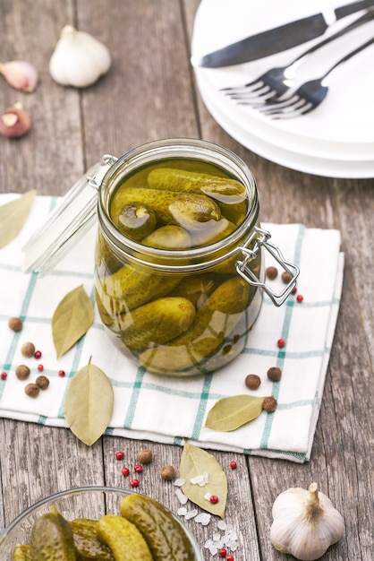 Concombres marinés aux herbes et épices sur table en bois.