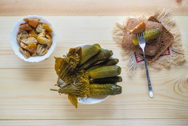 Concombres marinés et champignons marinés dans un bol sur une table rustique en bois