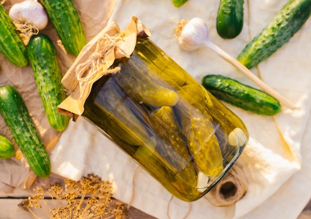 Concombres marinés salés dans un bocal sur une table en bois dans le jardin Concombres herbes aneth ail Préservation conservation Arrière-plan copie espaceVue de dessus