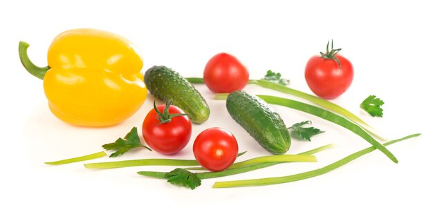 Concombres, poivrons, tomates et oignons verts isolés sur une surface blanche