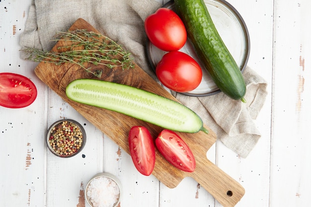 Concombres et tomates frais sur un fond blanc en bois