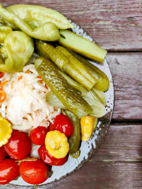 Concombres et tomates marinés dans une assiette sur une table en bois.