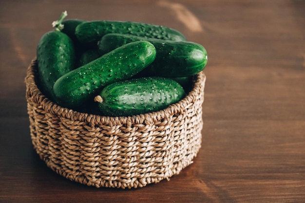 Concombres verts frais dans un panier en osier sur fond de table en bois Copiez l'espace vide pour le texte